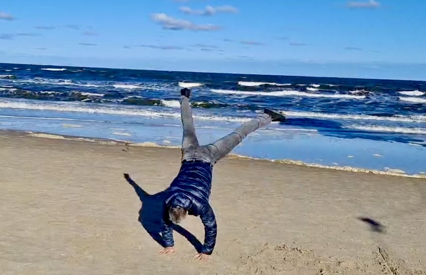 Handstand am Strand vor blauem Meer und Himmel